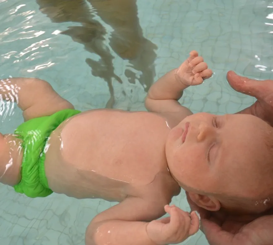 Instructor holding a baby on its back in the pool