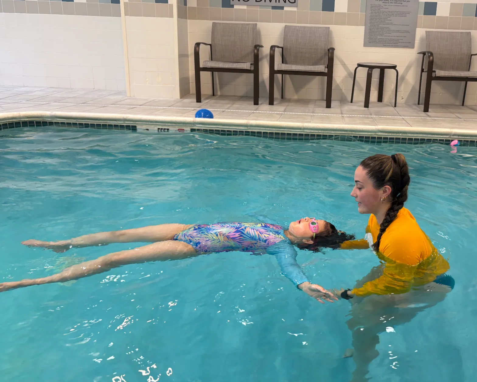 School-age swimmer doing a back float with an instructor